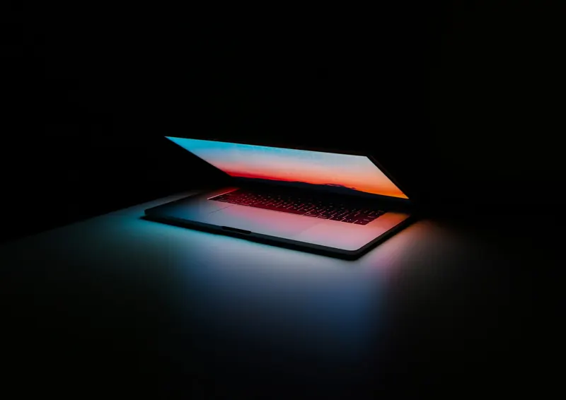 Laptop semichiuso illuminato al buio